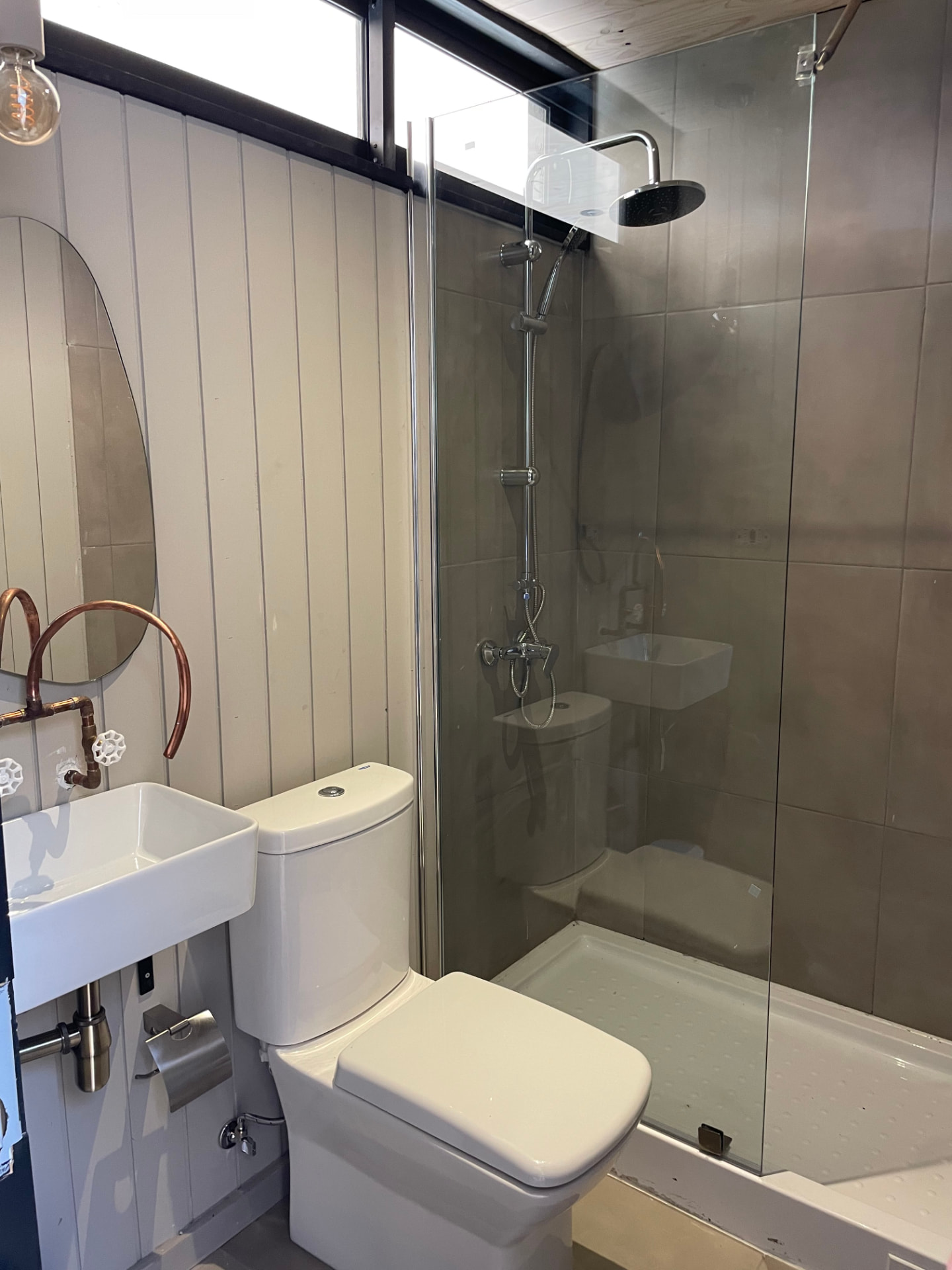 Baño con ducha acristalada y detalles en cobre